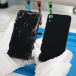 Hand hält kaputtes iPhone und Ersatz-Backcover